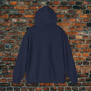 May include: A navy blue hoodie with a hood, long sleeves, and a kangaroo pocket. The back of the hoodie is visible, showcasing its solid color and simple design. The hoodie is made of a soft material.