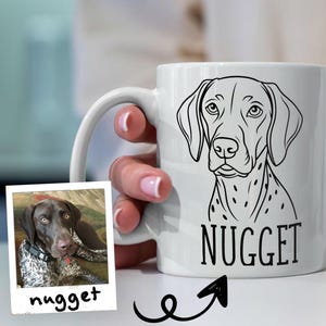 Puede incluir: Taza de cerámica blanca con un dibujo lineal negro de un perro y el nombre "NUGGET". Una pequeña foto del perro está al lado de la taza. La taza tiene un asa curvada.