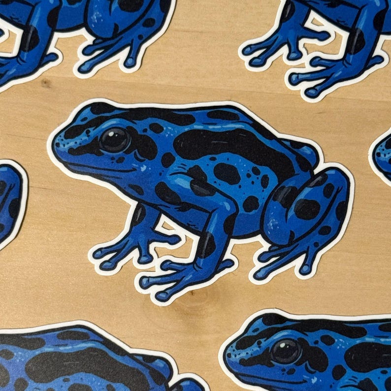 May include: A collection of stickers featuring a vibrant blue poison dart frog with distinct black spots and patches. The frog is depicted in a side profile view with a smooth skin texture, large dark eyes, and four webbed feet, rendered in a graphic illustration style.