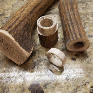 May include: A handcrafted antler ring and pieces of antler material. The ring is off-white with brown marbling. The antler pieces are brown with darker brown striations. The ring is approximately 0.75 inches in diameter.