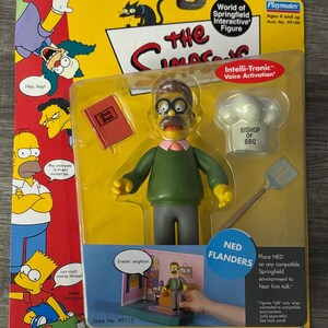 May include: A Playmates "World of Springfield" interactive figure of Ned Flanders, packaged in a yellow and red blister pack. The figure is wearing a green sweater, gray pants, and glasses. Accessories include a cookbook and a chef's hat.