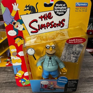 May include: A packaged "World of Springfield Interactive Figure" featuring Grampa Simpson. The figure is in a clear plastic blister pack with a yellow and red cardboard backing. The figure is wearing glasses, a light blue shirt, and blue pants. Includes a magnifying glass and newspaper.