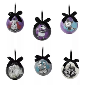 May include: Six round Christmas ornaments with black bows and hanging ribbons. Each ornament features a different character from The Nightmare Before Christmas, with a glittery background. The ornaments are in shades of purple, blue, and white.