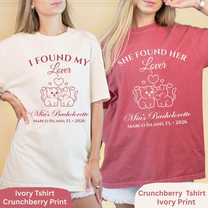 May include: Two t-shirts, one ivory and one crunchberry, with matching ivory print. The ivory shirt reads "I Found My Lover" and the crunchberry shirt reads "She Found Her Lover". Both shirts feature a cat graphic and "Mia's Bachelorette" text.