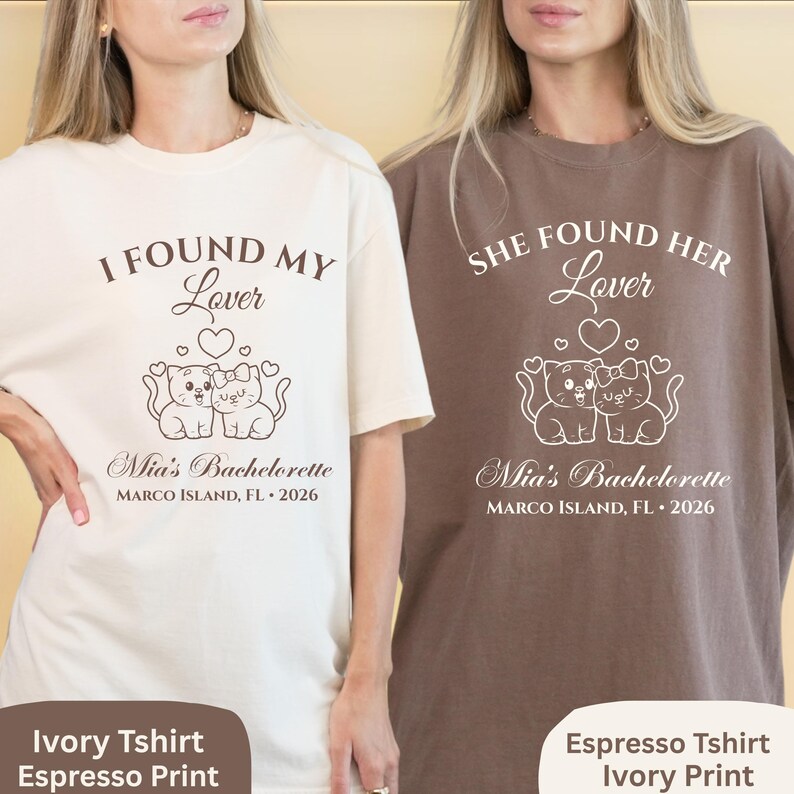 May include: Two t-shirts, one ivory and one espresso, with white graphic text and illustrations. The ivory shirt reads "I Found My Lover" above a cat design, and the espresso shirt says "She Found Her Lover". Both shirts include "Mia's Bachelorette" and location details.