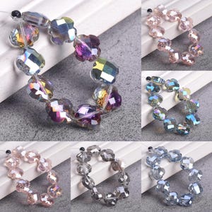 May include: Assortment of iridescent flower-shaped beads in various colors, including purple, pink, and blue. The beads are strung together, showcasing their faceted surfaces and reflective qualities. Ideal for jewelry making or craft projects.