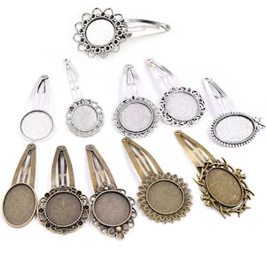 Könnte beinhalten: Eine Sammlung von Haarspangen aus Metall in verschiedenen Designs. Die Spangen haben runde und ovale Fassungen, einige mit dekorativen Rändern. Die Farben sind Silber und Antik-Bronze.