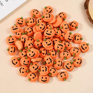 May include: A large collection of small, orange, pumpkin-shaped charms. Each pumpkin features a carved jack-o'-lantern face with black eyes, a nose, and a jagged mouth, topped with a small green stem. These miniature decorations are uniform in colour.