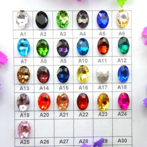 May include: A chart showing a selection of oval gemstones in a range of colours, including clear, black, green, blue, and orange. Each gem is labelled with a letter and number combination, such as A1, A2, and A3.