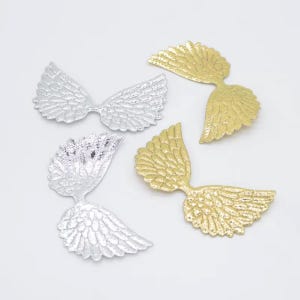 May include: Four decorative metal wing charms in silver and gold. The wings are detailed with feather-like textures and are arranged on a white surface. These charms are suitable for jewelry making, scrapbooking, or other craft projects.