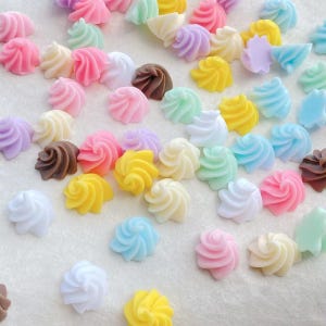 Può includere: Una collezione di abbellimenti in resina a forma di spirale colorati in vari colori pastello, tra cui rosa, giallo, blu, verde, bianco e marrone. Questi pezzi decorativi sono ideali per l'artigianato e i progetti fai-da-te.