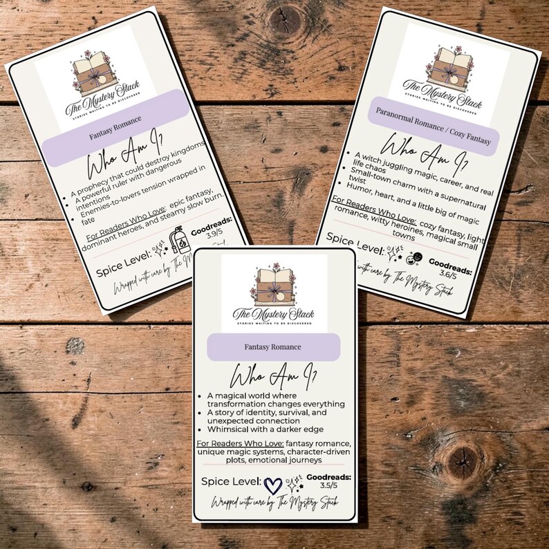 May include: Three white cards with text on a wooden surface. The cards feature the logo "The Mystery Stack" and the title "Who Am I?" with descriptions of fantasy and paranormal romance stories. The cards also include Goodreads ratings and spice levels.