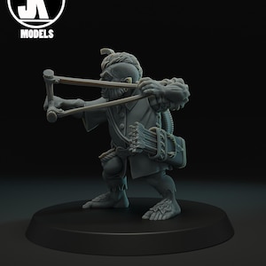 May include: A gray miniature figure of a fantasy character, holding a slingshot. The figure is in a combat stance, with a quiver of arrows on its back. The figure is on a black base, with the "JK MODELS" logo in the upper left corner.