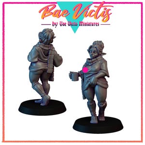 May include: Two gray miniature figurines of a person, one from the back and one from the front, holding a mug. The figurines are on black bases. The text "Bae Victis" and "by Vae Victis Miniatures" is at the top.