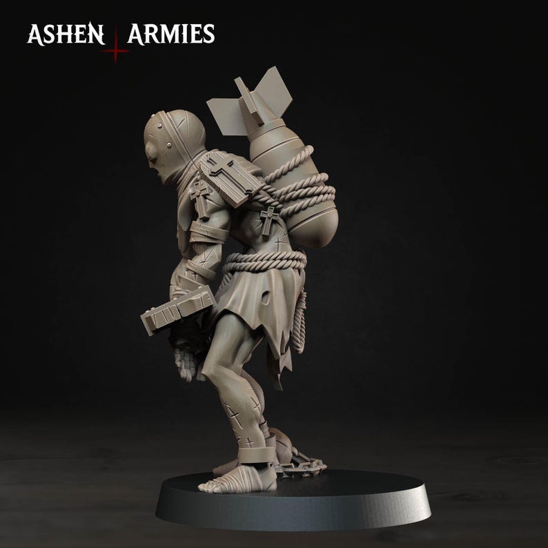 May include: A grey miniature figurine from Ashen Armies depicting a humanoid figure wearing a helmet and tattered clothing, carrying a large bomb strapped to its back with rope. The figure features cross symbols on its shoulders and legs.