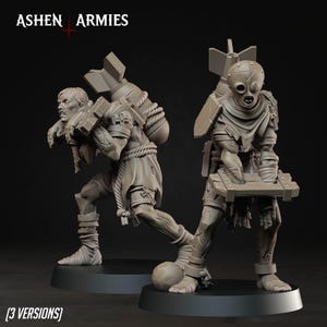 May include: Two unpainted gray resin miniature figures from Ashen Armies. One figure wears a mask and carries a wooden crate, while the other carries a large bomb on their back. Both figures feature tattered clothing, rope bindings, and circular bases.