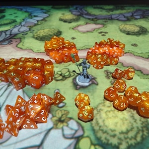 May include: An assortment of orange and clear polyhedral dice with white numbering, scattered on a map. A miniature figure stands in the center. The dice are of various shapes and sizes, including D4, D6, D8, D10, D12, and D20, perfect for tabletop gaming.
