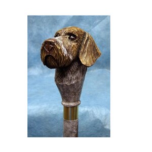 May include: A wooden walking stick with a carved German Shorthaired Pointer dog head.