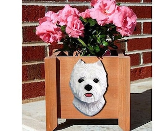 May include: A wooden planter box with a carved white dog face on the front. The planter is filled with vibrant pink flowers and green foliage. The box is made of light brown wood and sits on a concrete surface.