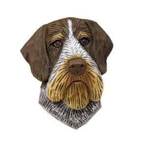 May include: A hand-carved wooden sculpture of a German Shorthaired Pointer dog's head. The sculpture is painted in shades of brown, white, and black, with realistic details.