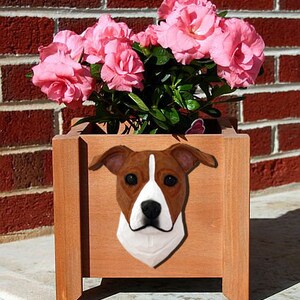May include: A brown and white dog planter with a brown wooden planter box. The planter box is filled with pink flowers.