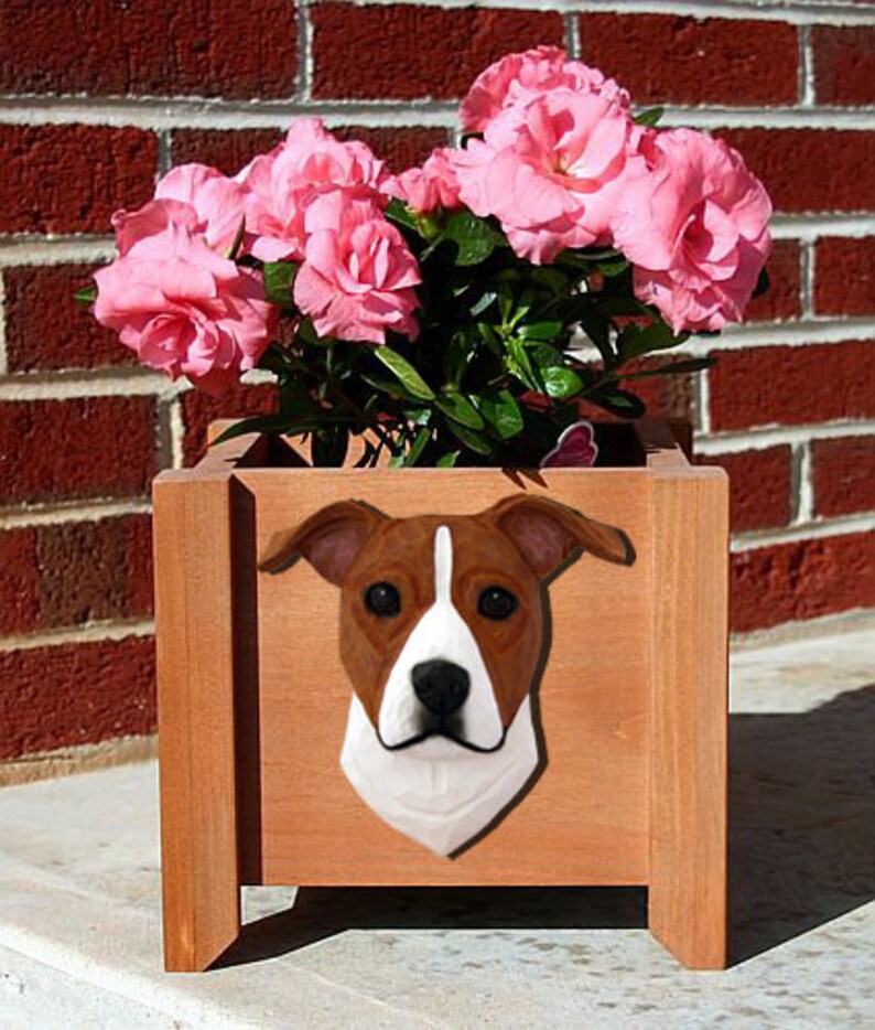 May include: A brown and white dog planter with a brown wooden planter box. The planter box is filled with pink flowers.