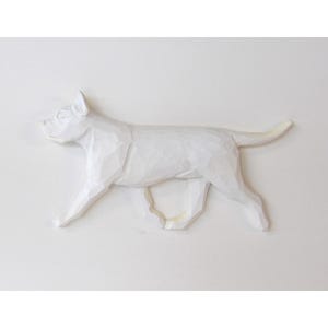 May include: A white, carved wooden dog sculpture in a running pose. The dog is depicted with detailed features and a textured surface, showcasing its form against a plain white background. The sculpture is a decorative item.