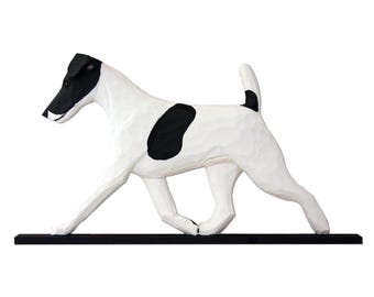 May include: A hand-carved wooden figurine of a dog in a walking pose, featuring a white body with black markings on the head, back, and tail. The dog is mounted on a thin, rectangular black wooden base, showcasing visible carved texture throughout.