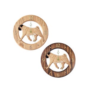 May include: Two wooden wall clocks featuring a carved pug dog design. The clocks have a circular frame with the numbers 3, 6, 9, and 12. One clock has a light wood finish, and the other has a dark wood finish.