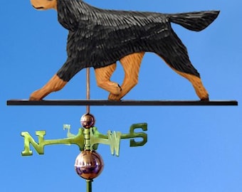 May include: A black and tan wooden  Gordon Setter dog weather vane with a black metal base and a copper colored arrow. The vane is mounted on a wooden post.