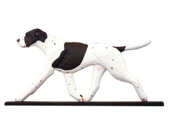 Peut inclure: Sculpture en bois d'un chien en mouvement. Le chien est principalement blanc avec des marques marron sur la tête, le dos et la queue. La sculpture est montée sur une base marron foncé, créant un contraste saisissant sur fond blanc.