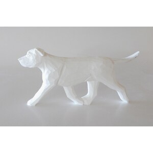 May include: A white, geometric-style dog sculpture. The dog is depicted in a walking pose, with its tail slightly raised. The sculpture has a faceted design, giving it a modern and artistic look. The dog is a solid white color.