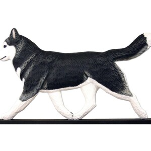 Pu&ograve; includere: Una statuetta di legno di un cane Husky siberiano che corre, dipinta in bianco e nero. La statuetta &egrave; dipinta a mano e ha un aspetto realistico.