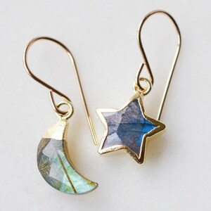Natural labradorite moon and star stone earrings in gold. One earring is a star the other a crescent.