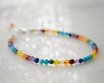 May include: A rainbow gemstone bracelet with small, round beads in various colors, including red, orange, yellow, green, blue, and purple. The bracelet is made with a silver clasp.