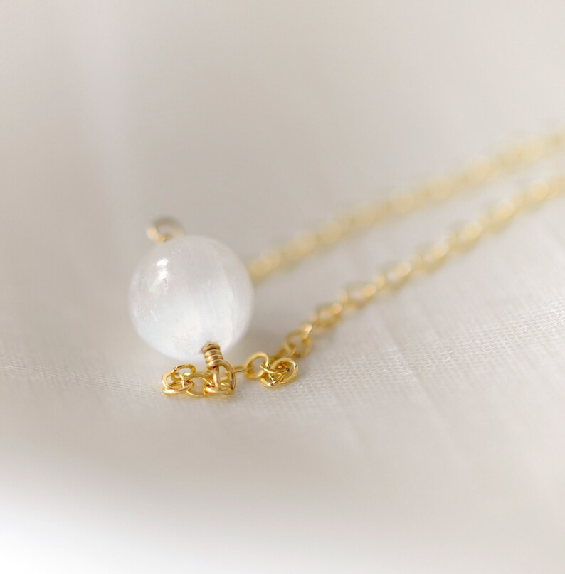 Pode incluir: Um delicado colar de corrente de ouro com um &uacute;nico pingente de cristal de selenite branco.