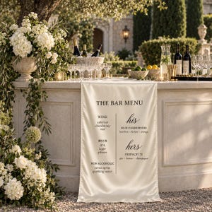May include: A cream-colored satin bar menu runner featuring black text that reads THE BAR MENU, listing wine, beer, and non-alcoholic options on the left, and his and hers cocktail selections including Old Fashioned and French 75 on the right.