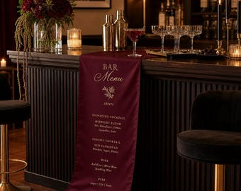 Peut inclure: Un chemin de table de bar bordeaux profond avec le texte imprimé en blanc "BAR Menu", "cheers" et une liste de cocktails signature, cocktails classiques, vins et bières. Le chemin est drapé sur un comptoir de bar en bois sombre.