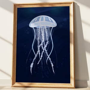 May include: A framed art print featuring a jellyfish illustration. The jellyfish is depicted in white and light blue against a dark blue background. The artwork is encased in a light brown wooden frame.