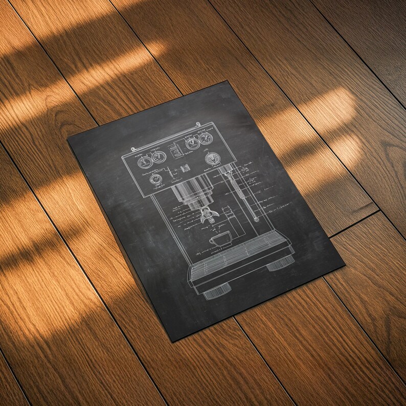 May include: A black rectangular print featuring a detailed white line drawing of an espresso machine. The machine's components, including dials, a portafilter, and a cup, are clearly depicted. The print is set against a dark background.