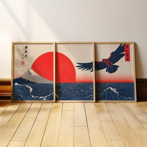 May include: Three framed art prints depicting a Japanese landscape. The artwork features a red sun, Mount Fuji, ocean waves, and a soaring eagle. The prints are in a traditional Japanese style with a wood frame.