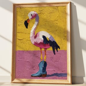 May include: A framed painting of a flamingo wearing a blue cowboy boot. The flamingo is pink, white, and purple, set against a textured yellow and pink background. The artwork is in a wooden frame.