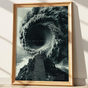 May include: A framed black and white art print featuring a dramatic swirling vortex above a rocky landscape with a staircase leading to a figure. The print has text at the top and bottom, and is set in a light brown wooden frame.