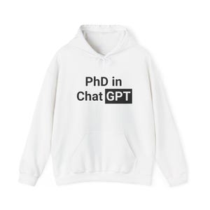 Può includere: Felpa con cappuccio bianca con tasca frontale e coulisse. Il testo "PhD in Chat GPT" è stampato in nero sul davanti. Un capo in stile casual.