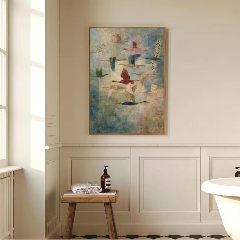 May include: A framed artwork featuring a flock of birds in flight. The birds are depicted in various colors, including red, green, and blue, against a muted, textured background. The artwork is displayed in a bathroom setting.