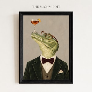 May include: A framed wall art print titled THE MAXIM EDIT featuring an anthropomorphic alligator wearing a dark green blazer, a brown tweed vest, a white collared shirt, a dark red bow tie, and brown glasses, balancing a cocktail glass.