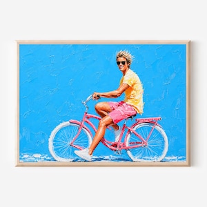 May include: A framed painting shows a person on a red bicycle against a textured blue backdrop. The person wears a yellow top, pink shorts, and white trainers. The bicycle has white tyres and a classic design.