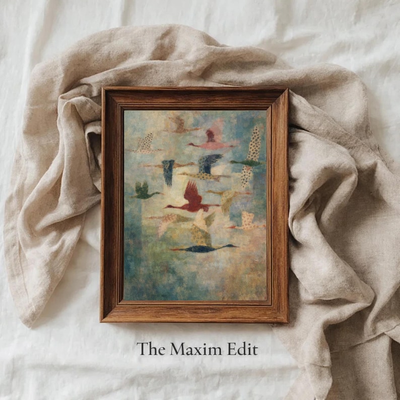 May include: A framed art print featuring a flock of birds in flight. The birds are depicted in various colors, including red, pink, and green, against a blue and green background. The frame is a dark brown color. The text "The Maxim Edit" is at the bottom.