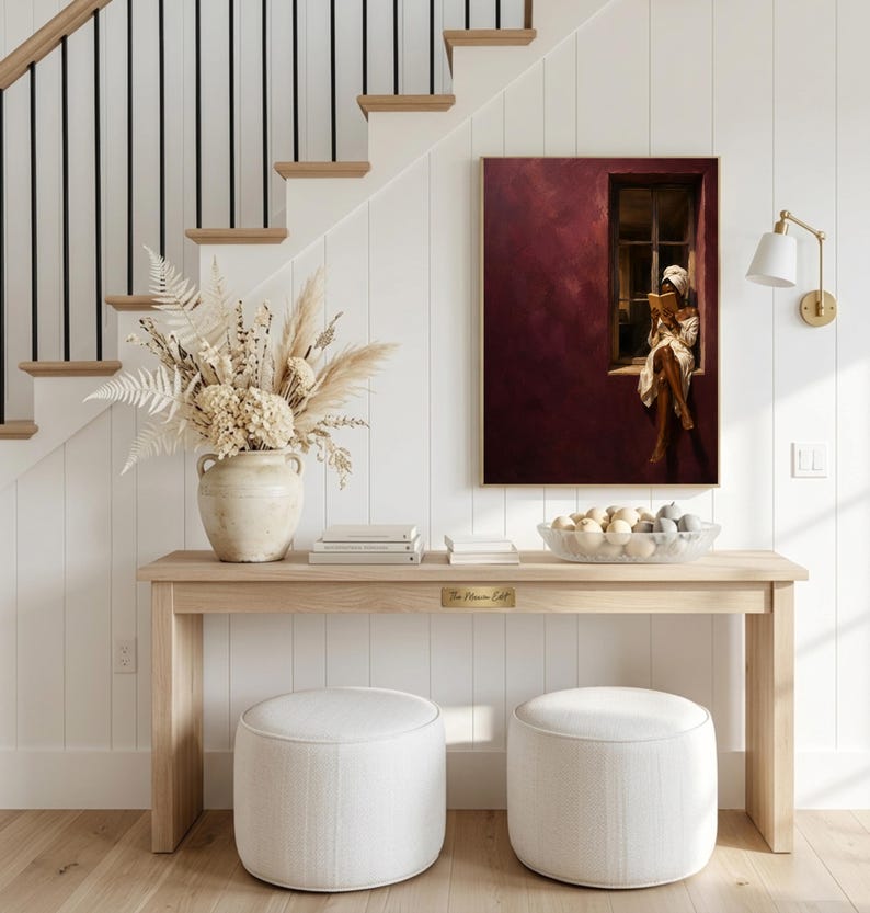 Painting of a Black woman in a white towel reading a golden book on a sunlit windowsill against a deep burgundy wall, moody figurative wall art print.