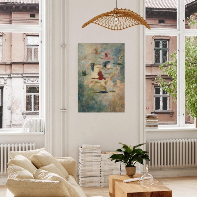 May include: An abstract art print featuring a flock of birds in flight against a muted blue and green background. The birds are depicted in various colors, including red, pink, and black, with some having patterned wings. The artwork is displayed in a bright, airy living room.